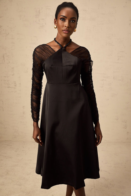 A black halterneck midi dress with panel details worn by a model against a plain background
