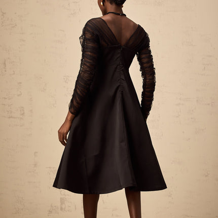 A black halterneck midi dress with panelled design on a female model