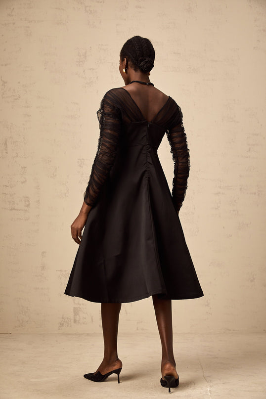 A black halterneck midi dress with panelled design on a female model