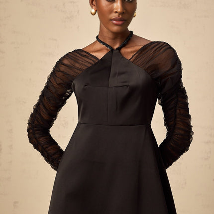 A black halterneck midi dress with panelled design worn by a model standing against a plain background