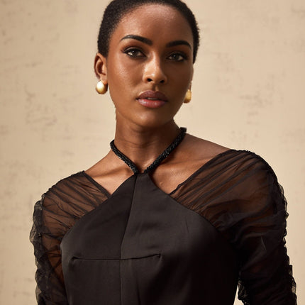 A black halterneck midi dress with panels worn by a model standing against a plain background