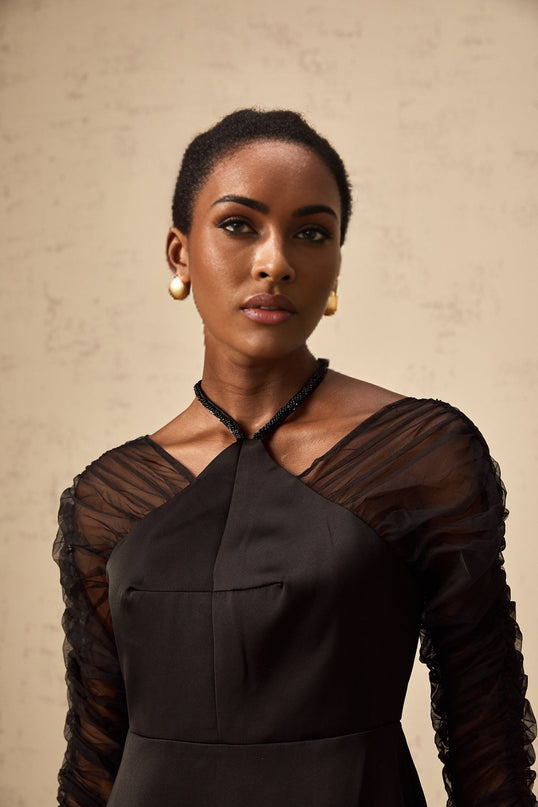 A black halterneck midi dress with panels worn by a model standing against a plain background