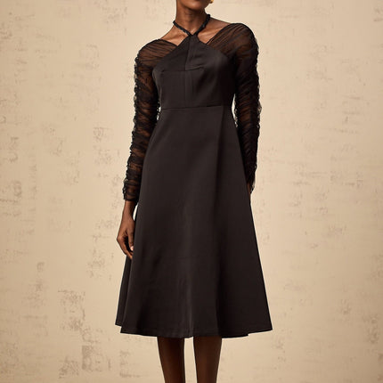 A black halterneck midi dress with panels worn by a model standing against a plain background