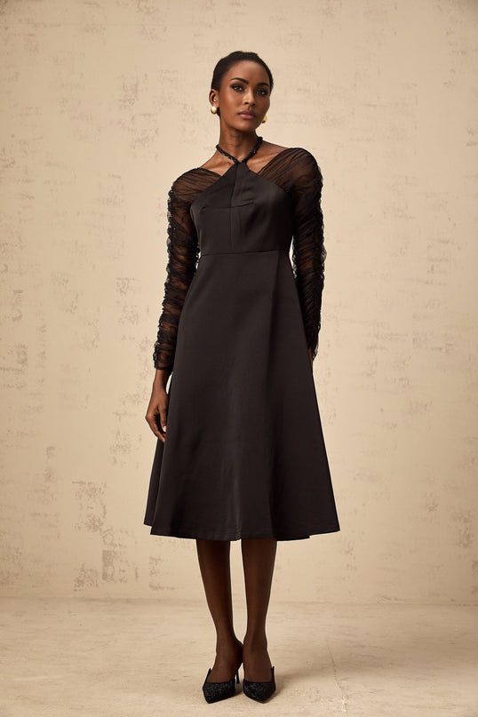 A black halterneck midi dress with panels worn by a model standing against a plain background