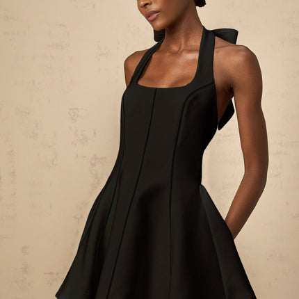 A black halterneck mini dress with a bow detail featuring a sleek and stylish design by Quirine