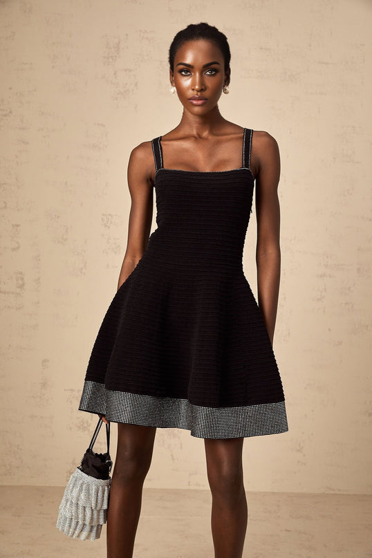 A black knit mini dress with a flared skirt and studded embellishments worn by a model