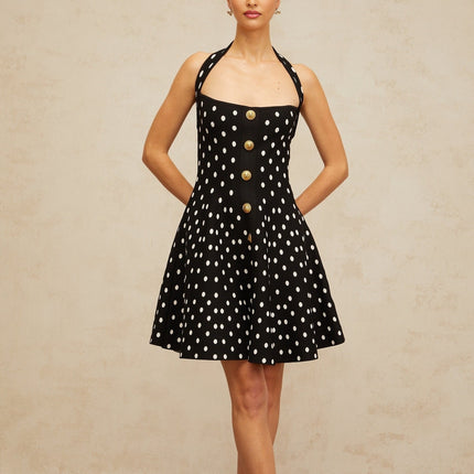 A black knit mini dress with white polka dots featuring short sleeves and a fitted silhouette called Sandrine