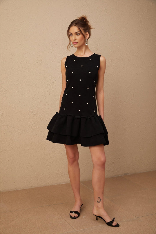 A black knitted mini dress adorned with small beaded embellishments featuring a fitted silhouette and short hemline