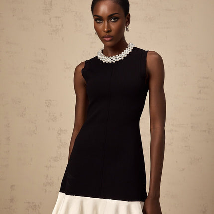 A black knitted mini dress with ruffled details and faux pearl embellishments featuring a short hemline and fitted silhouette