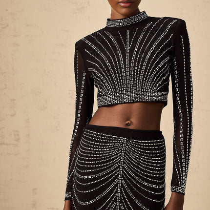 A black matching set featuring a mesh top and skirt adorned with rhinestone embellishments