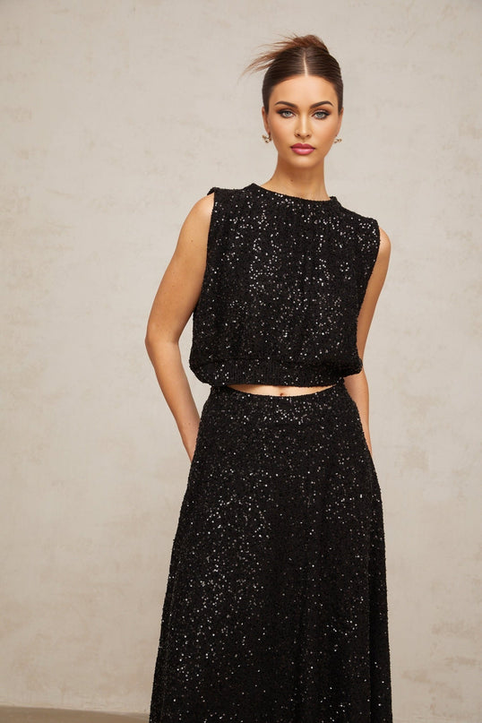 A black matching set featuring a sequined knit vest and skirt with sparkly details and a coordinated design