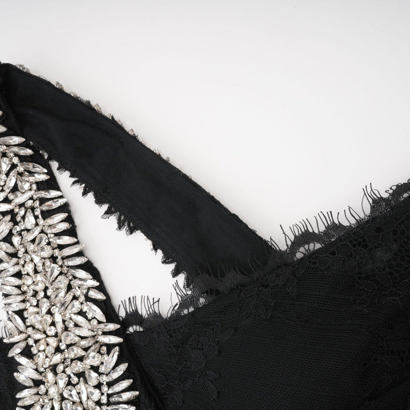 A black maxi dress with a crossover bodice adorned with crystal embellishments featuring long sleeves and a flowing skirt