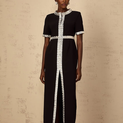 A black maxi dress with a front slit and crystal embellishments worn by a model standing against a plain background
