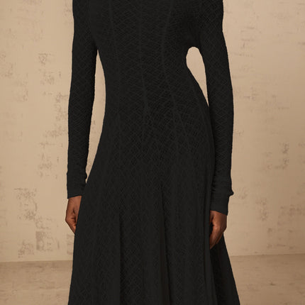 A black maxi dress with a wavy lace pattern featuring a long flowy silhouette and delicate lace detailing throughout