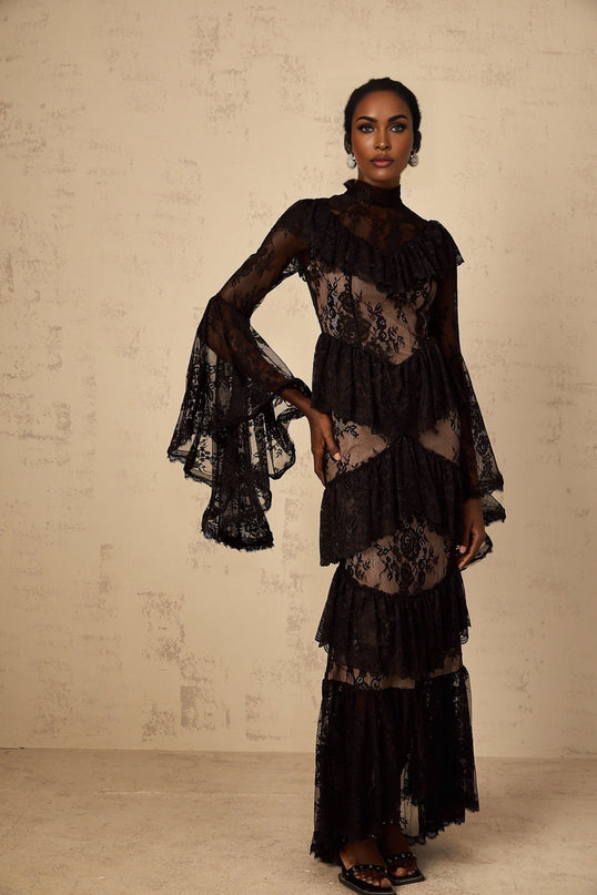 A black maxi dress with floral lace pattern and ruffled details named Roxane