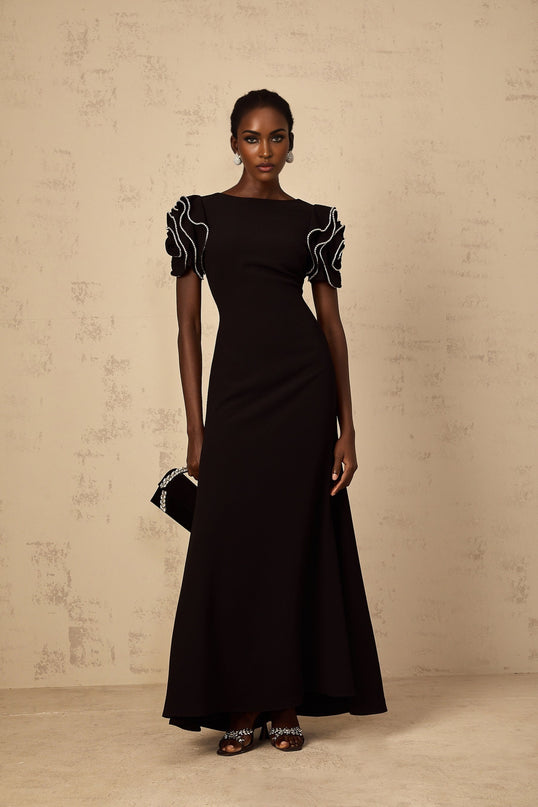 A black maxi dress with ruffled details and embellishments by Bruyere featuring a long flowing silhouette