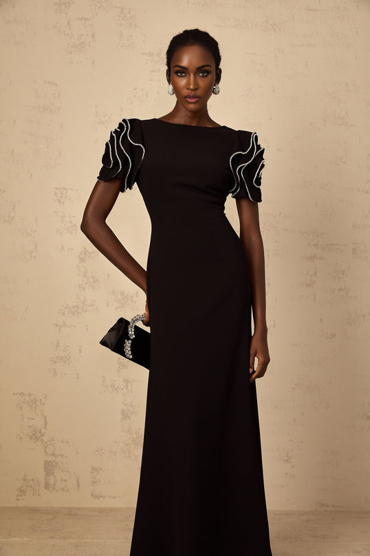 A black maxi dress with ruffled details and embellishments by Bruyere featuring a long flowing silhouette