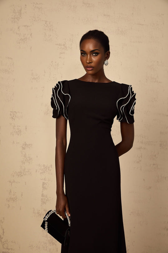A black maxi dress with ruffled details and embellishments by Bruyere featuring a long flowing silhouette