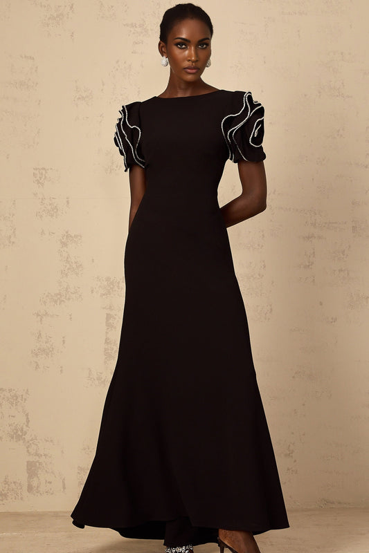 A black maxi dress with ruffled details and embellishments featuring a long flowy silhouette and elegant design by Bruyere