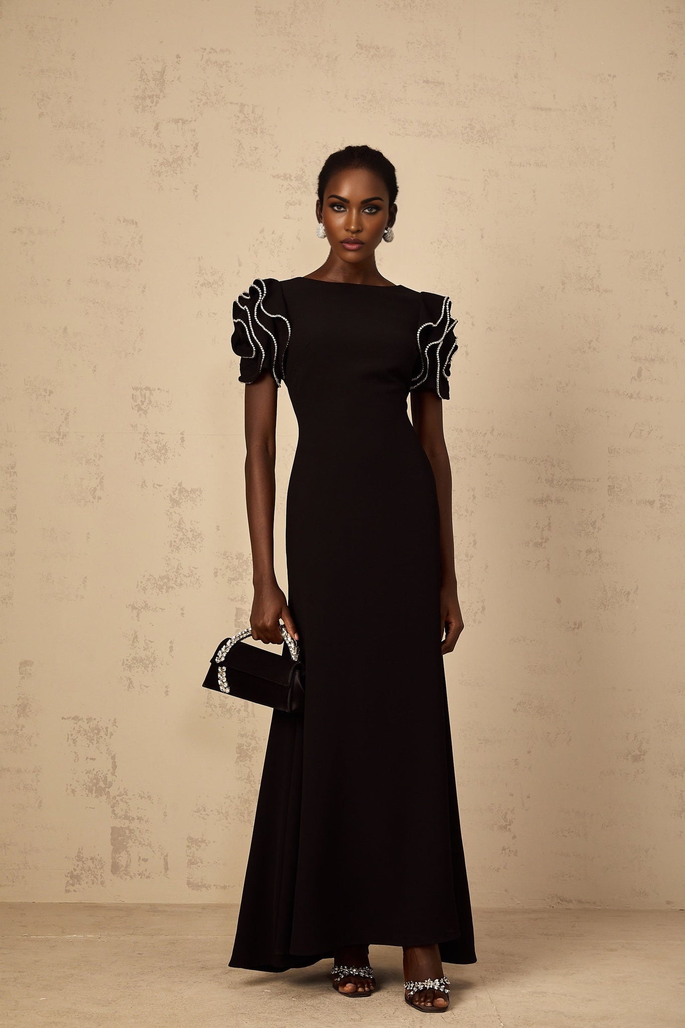 A black maxi dress with ruffled details and embellishments made by Bruyere featuring a long flowing skirt and elegant design