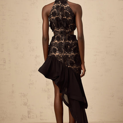 A black midi dress with an asymmetric hem featuring colorful floral applique details and a fitted silhouette