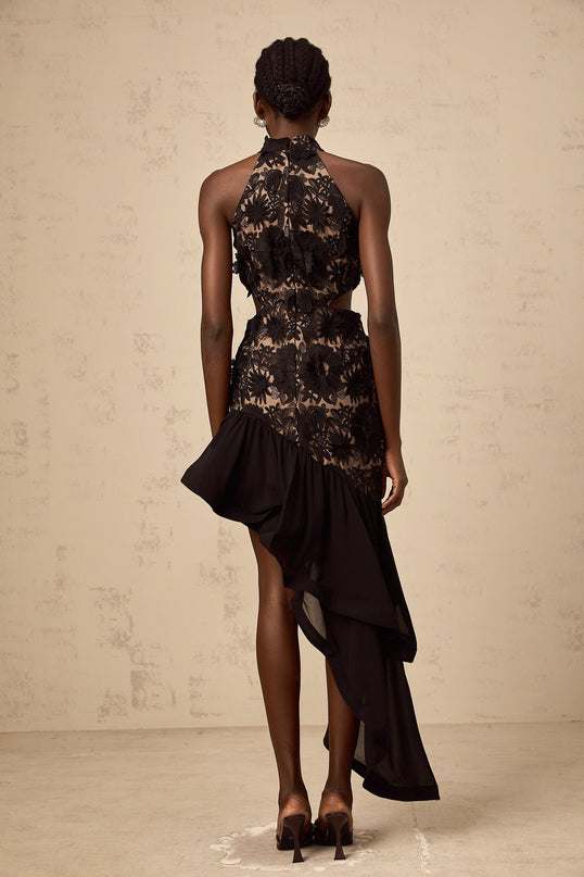 A black midi dress with an asymmetric hem featuring colorful floral applique details and a fitted silhouette