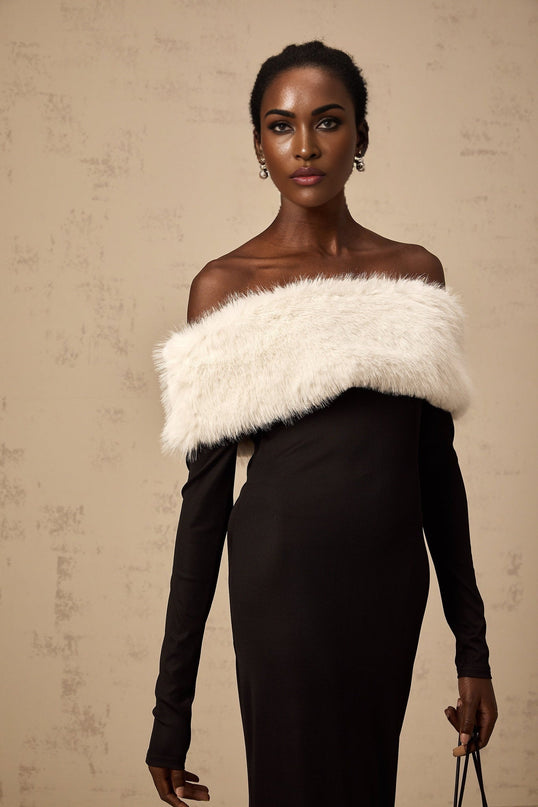 A black midi dress with an offshoulder neckline and faux fur trim worn by a model standing against a plain background