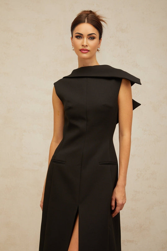 A black midi dress with an open back and deconstructed design worn by a model standing against a plain background