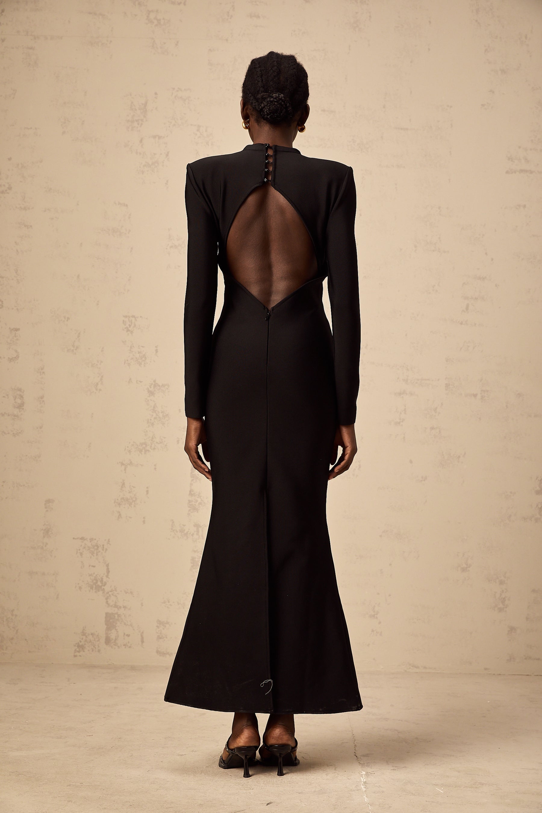 A black midi dress with cutout details featuring a sun motif pattern and ruched fabric Astrid style with a formfitting silhouette