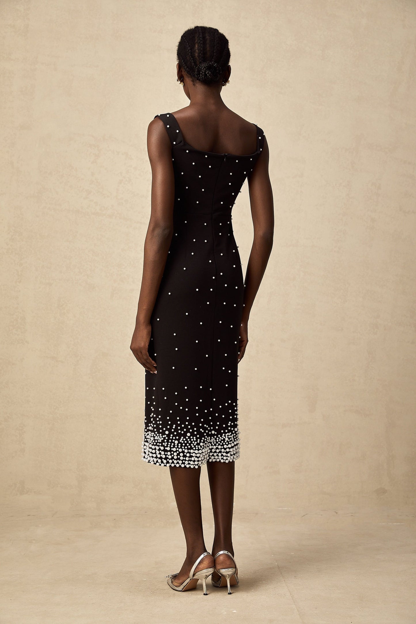 A black midi dress with faux pearl embellishments on the bodice named Apolline