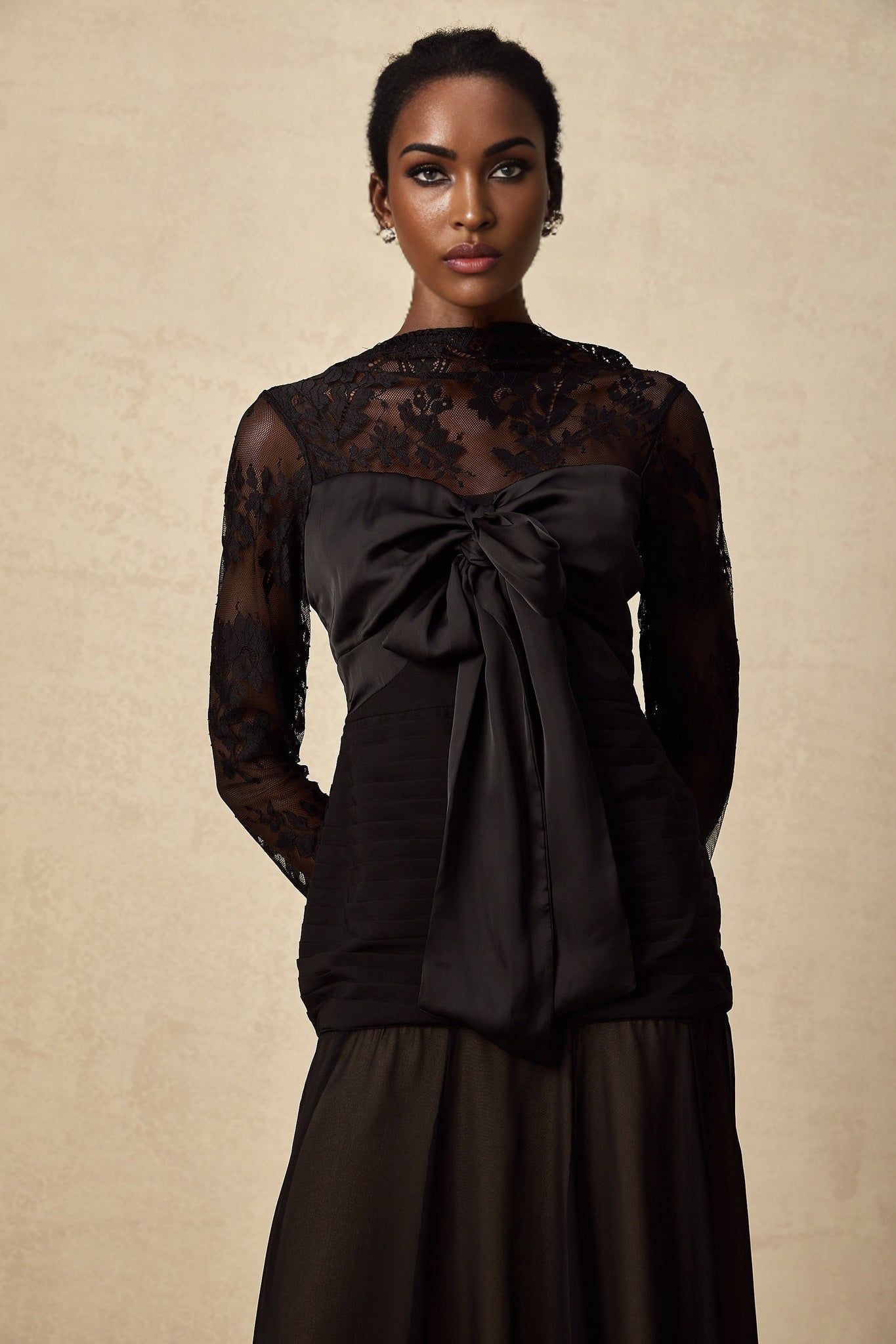 A black midi dress with floral lace panels named Amelie featuring a fitted silhouette and delicate floral patterns throughout the fabric