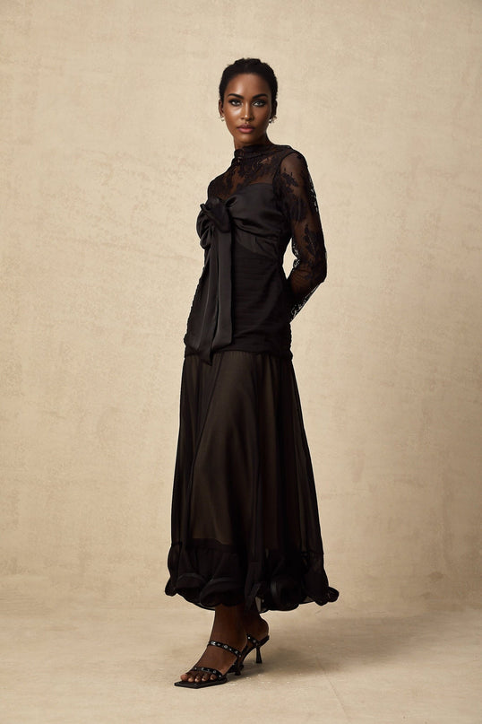 A black midi dress with floral lace panels named Amelie featuring a fitted silhouette and intricate lace detailing throughout the bodice and skirt