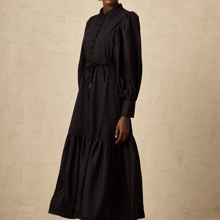 A black midi dress with intricate lace embroidery details styled on a mannequin against a plain background