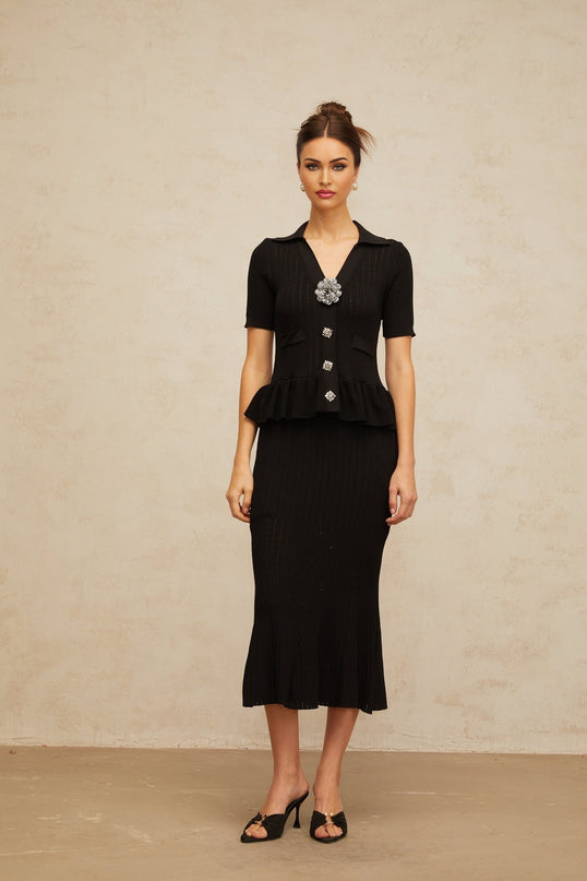 A black midi dress with intricate pointelle knit pattern and embellishments featuring a fitted silhouette and delicate details