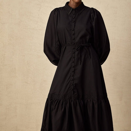 A black midi dress with lace embroidery detail featuring a fitted silhouette and delicate floral patterns