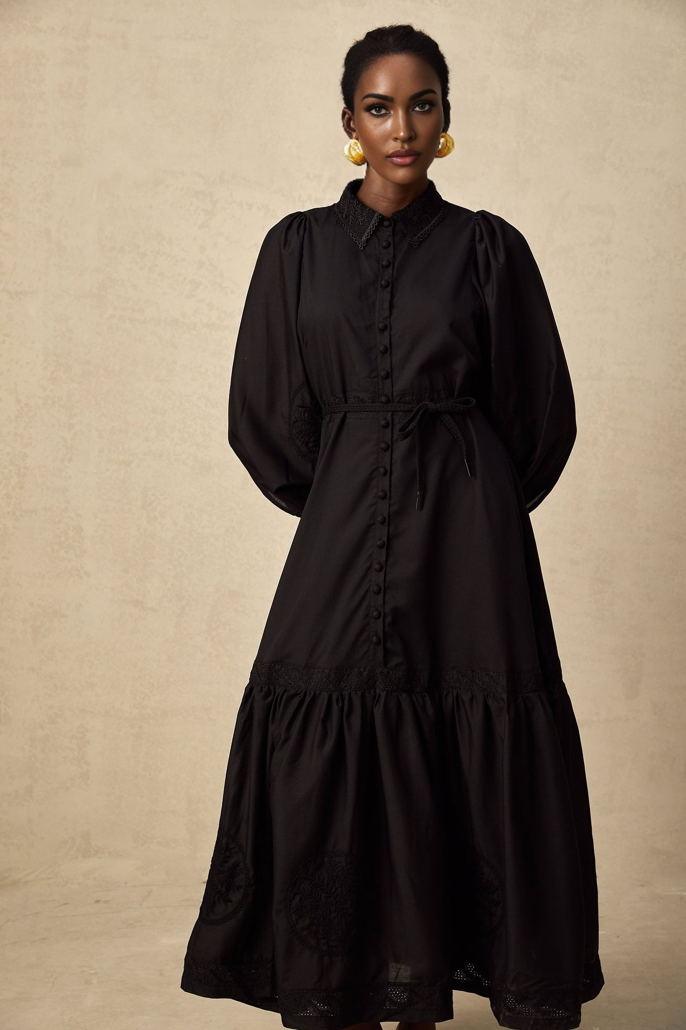 A black midi dress with lace embroidery detail featuring a fitted silhouette and delicate floral patterns