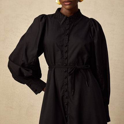 A black midi dress with lace embroidery details featuring a sheer floral pattern throughout the bodice and sleeves