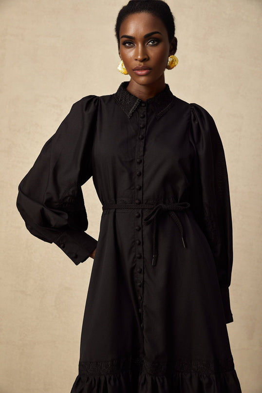 A black midi dress with lace embroidery details featuring a sheer floral pattern throughout the bodice and sleeves