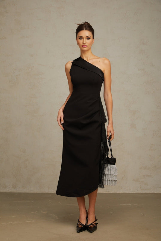 A black midi dress with lace panels and an asymmetric hemline worn by a model