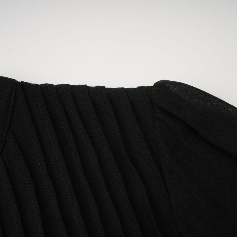 A black midi dress with pleated details and a buttonfront design featuring long sleeves and a fitted silhouette
