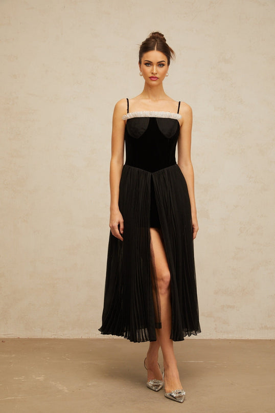 A black midi dress with velvet panels and pleated design featuring long sleeves and a flowy silhouette named Clémence