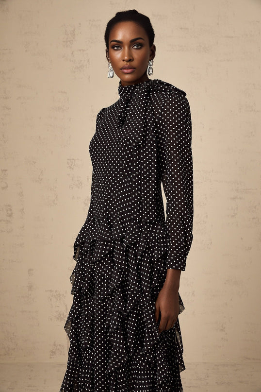 A black midi dress with white polka dots featuring ruffle details and a silhouette reminiscent of the Coraline style