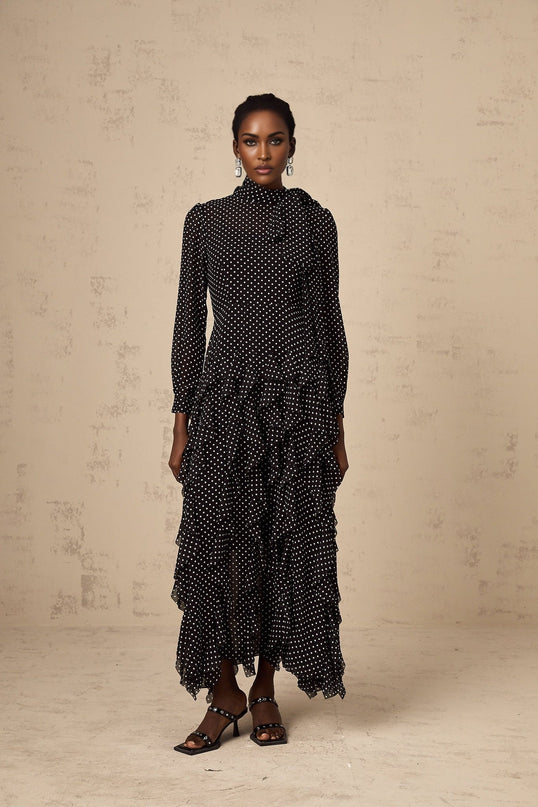 A black midi dress with white polka dots featuring ruffled details and a feminine silhouette named Coraline