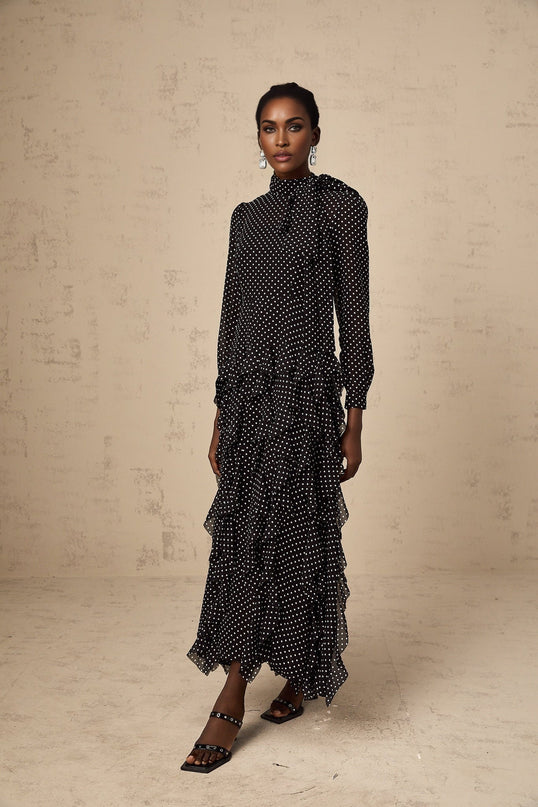 A black midi dress with white polka dots featuring ruffled details and a feminine silhouette
