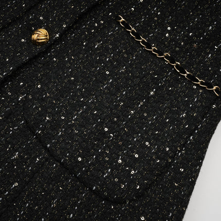 A black mini dress with a combination of tweed fabric and sequin panels named Audrey featuring a short length and likely a fitted silhouette