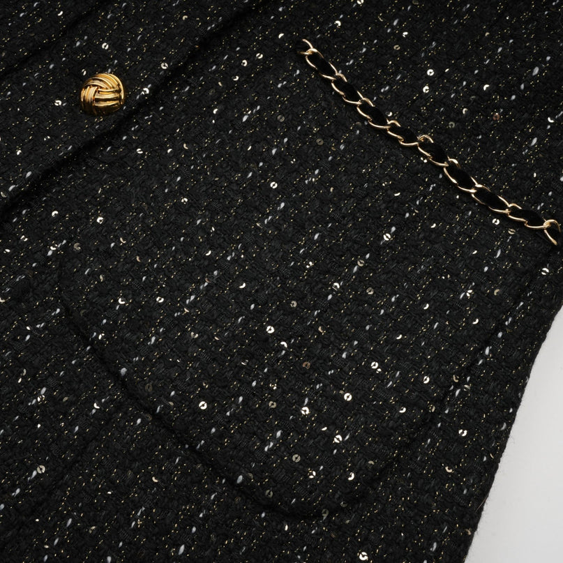 A black mini dress with a combination of tweed fabric and sequin panels named Audrey featuring a short length and likely a fitted silhouette