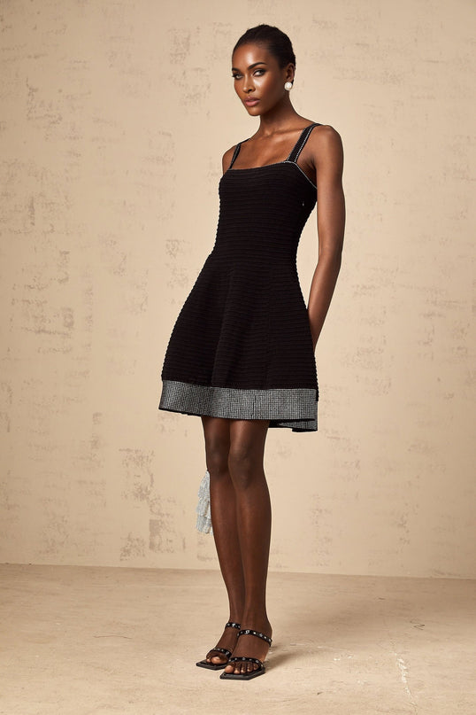 A black mini dress with a flared skirt and long sleeves made of knit fabric featuring studded embellishments throughout