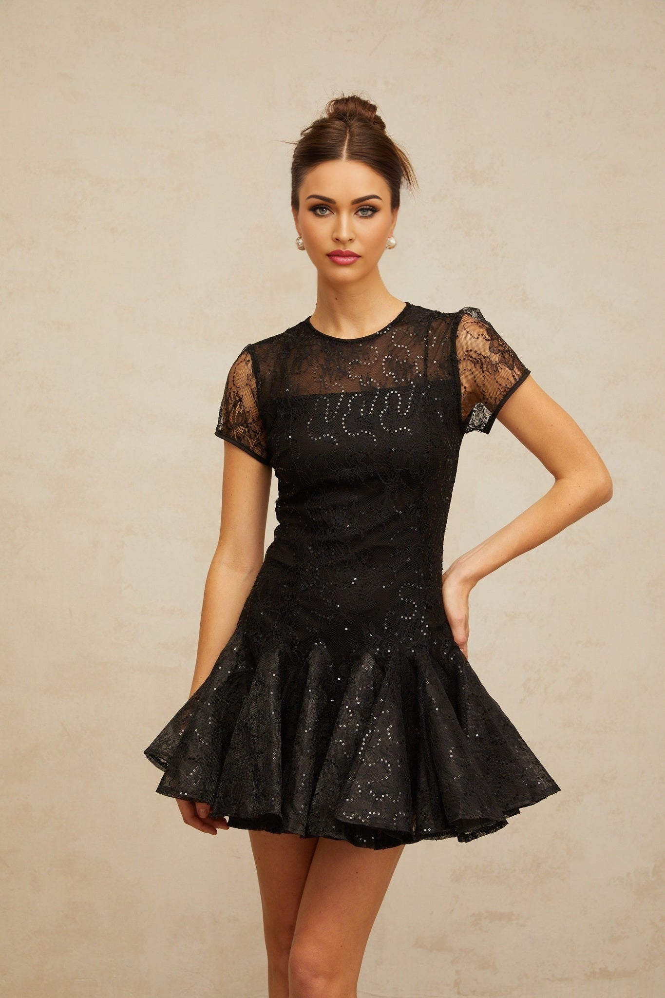 A black mini dress with a flared skirt covered in shimmering sequins called the Lara dress