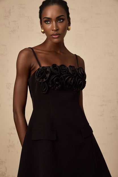 A black mini dress with a flared skirt featuring delicate rose appliques The dress has a fitted bodice and short hemline creating a feminine silhouette