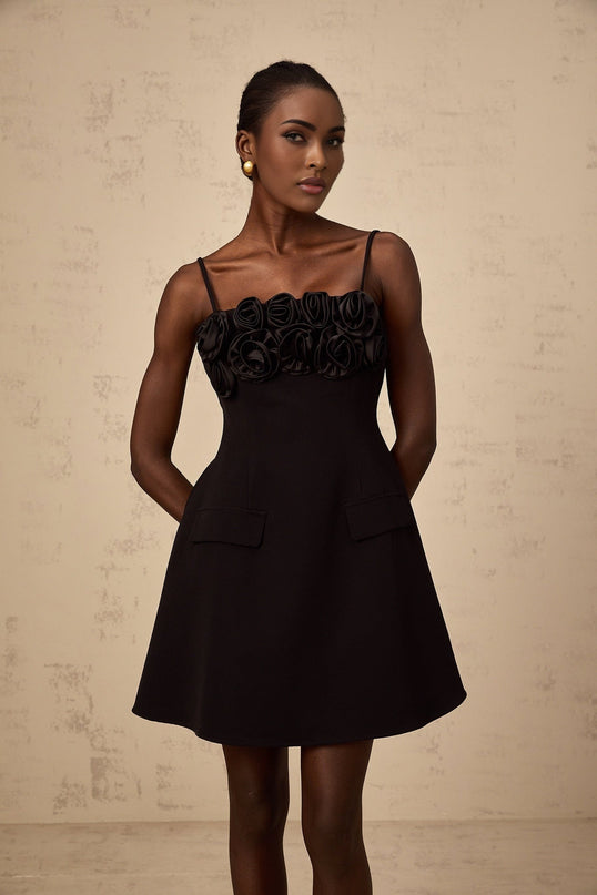A black mini dress with a flared skirt featuring rose appliqués and a fitted bodice